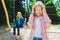 Portrait of offense child at park. On the background other girl riding a swing