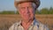 Portrait Of An Old Caucasian Farmer Agronomist In A Cowboy Hat On Wheat Field