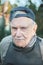 Portrait of an old farmer in a baseball cap. The 87 - year-old smiles and adjusts his baseball cap after work. Active ageing.