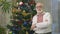 Portrait of old handsome man in embroidery near a Christmas tree