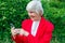 Portrait of old lady, grandmother makes selfie outdoors at sun day. modern granny finger touch the touchscreen her phone
