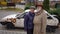 Portrait of old sad couple talking standing at background of car with bullet holes. Live camera zoom in to frustrated