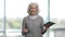 Portrait of and old slim lady holding tablet pc and talking.