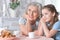 Portrait of old woman with a young girl drinking tea at home