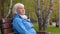 Portrait older relaxing on bench in autumn park and looking in sideway