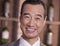 Portrait of older smiling businessman standing by wine bottles, close-up