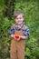 Portrait of one cute boy in a hat in the garden with a red apple, emotions, happiness, food. Autumn harvest of apples