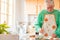 Portrait of one mature and old man cooking at home in the kitchen smiling. Senior preparing food to lunch alone indoor. Retired