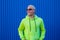 Portrait of one young man or teenager smiling and having fun wearing trendy sun glasses and lime sweater with blue colorful