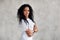 Portrait optimistic African American woman with long curly hair smiling, looking at camera, dressed in white T-shirt