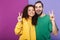 Portrait of optimistic caucasian couple man and woman in colorful clothing smiling while showing peace fingers