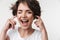 Portrait of optimistic woman with short brown hair in basic t-shirt plugging her ears with fingers