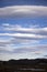 Portrait orientation three quarters of a sky filled with lenticular clouds over desert town and small pond by carson city