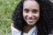 Portrait outdoors of a young afro american woman laughing. Green backgrou