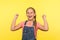 Portrait of overjoyed excited little girl in denim overalls shouting from happiness, showing yes gesture