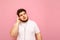 Portrait of overweight charismatic guy on a pink background listening to music in headphones and looking away with a serious face