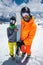 Portrait of a pair of young skiers athletes man and woman in ski masks with skis stand and look at the camera on the