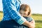 Portrait of parent and child. Mother hugs her little daughter. Nature background, rural landscape, green meadow, close-up of child