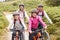 Portrait of parents and children sitting on mountain bikes in a country lane during a family camping trip, front view