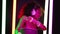 Portrait of party girl dancing to music with headphones on glowing multi-colored lamps in studio. Disco woman with curly