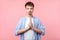 Portrait of peaceful brown-haired man with small beard and mustache holding hands in prayer. studio shot isolated on pink