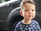 Portrait of pencive toddler boy on the background of the car.
