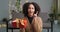 Portrait pensive afro american woman with stylish curly afro hairstyle sits on floor with red present holds gift box in