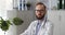 Portrait of pensive caucasian male doctor looking at camera in clinic office