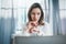 Portrait of pensive confident businesswoman working with laptop computer at modern office.Blurred background.