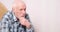 Portrait of a pensive elderly man with gray hair touching his beard and looking to the side. Copy space