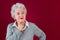 Portrait of pensive elderly woman with a red background