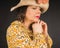 Portrait of a pensive mature woman in a straw hat and yellow dress with a floral pattern on a black background