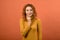 Portrait of pensive and optimistic redhead Caucasian girl in orange jumper  on orange studio background.