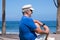 Portrait of pensive senior man at beach looking away. Retired enjoying summer holiday at sea