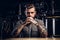 Portrait of a pensive tattooed hipster male with stylish beard and hair in the shirt in indie brewery.