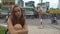 Portrait pensive woman sitting on city street and car traffic background. Face thoughtful and sad girl on street in