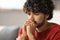 Portrait Of Pensive Young Indian Man Sitting On Couch At Home