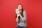 Portrait of pensive young woman in casual striped clothes holding teddy bear plush toy looking up isolated on bright red