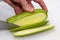 A portrait of a person cutting a courgette with a sharpp knife in a kitching while cooking a nice and delicious dinner