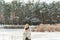 Portrait of petty young blond woman, dressed warmly, with a scarf and mittens. Beautiful girl enjoying in the snow