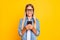 Portrait photo of preteen schoolgirl with big eyewear smiling keeping cellphone using social media isolated on bright