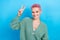 Portrait photo of young friendly person pink dyed hair woman wear green trendy shirt show v-sign peace isolated on blue