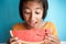 Portrait picture face of asian little girl looking watermelon slice on blue background. A cute girl so excited