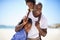 Portrait, piggyback and a black family on the beach in summer together for travel, freedom or vacation. Love, smile or