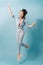 Portrait of playful crazy girl jumping in the air looking at camera enjoying weekend having perfect mood on light blue background