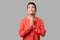 Portrait of pleading young woman with bun hairstyle, big earrings and in red blouse. indoor studio shot isolated on gray