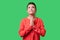 Portrait of pleading young woman with bun hairstyle, big earrings and in red blouse. indoor studio shot isolated on green