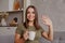 Portrait of pleasant young woman with mug looking at camera, waving hello. Pretty millennial lady communicating with