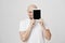 Portrait of pleased adult caucasian male model with beard covering half of face with tablet while advertising it and