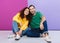 Portrait of pleased caucasian couple in colorful clothing smiling and hugging together while sitting on floor